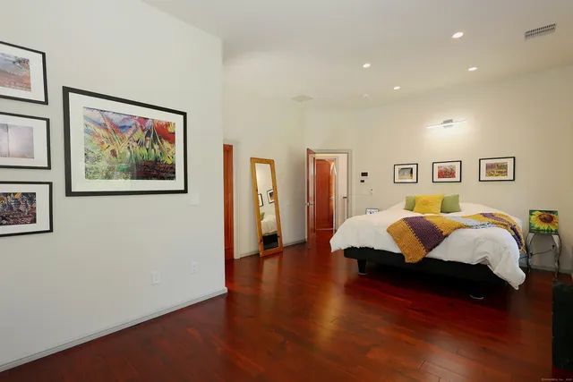 a spacious bedroom with a bed and a painting on the wall