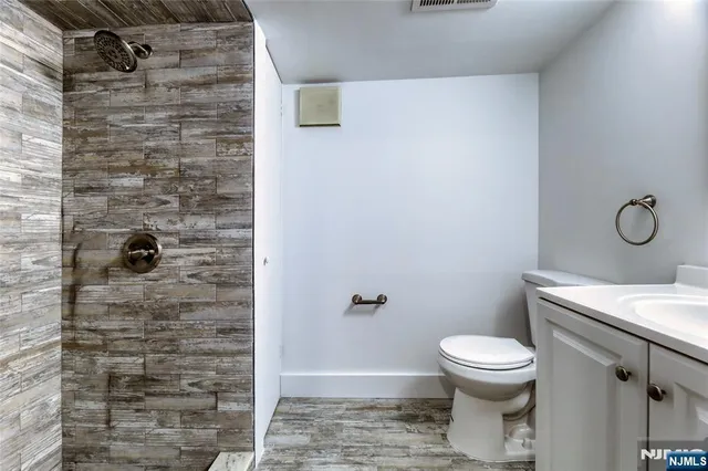 a bathroom with a granite countertop toilet a sink and shower