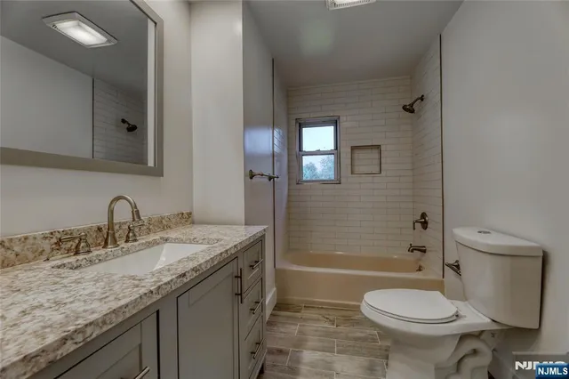 a bathroom with a granite countertop toilet a sink and a bathtub