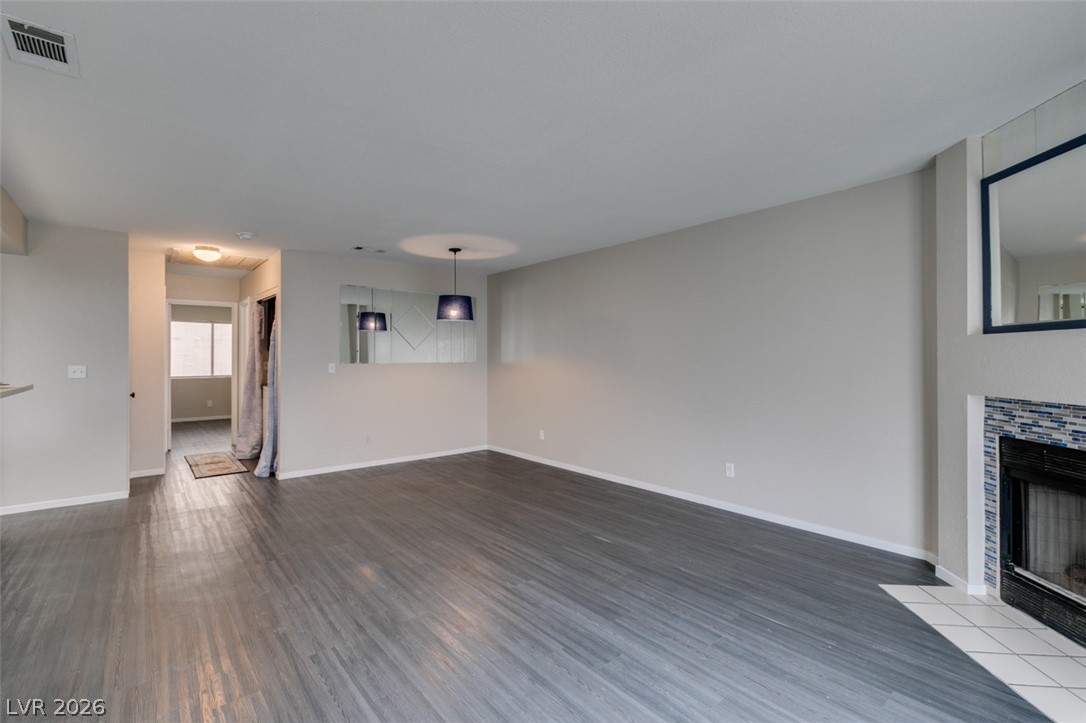 810 North Sloan Lane, Unit 103 Las Vegas, NV 89110 - Photo 13 of 16 Unfurnished living room featuring a tile fireplace, wood finished floors, and baseboards