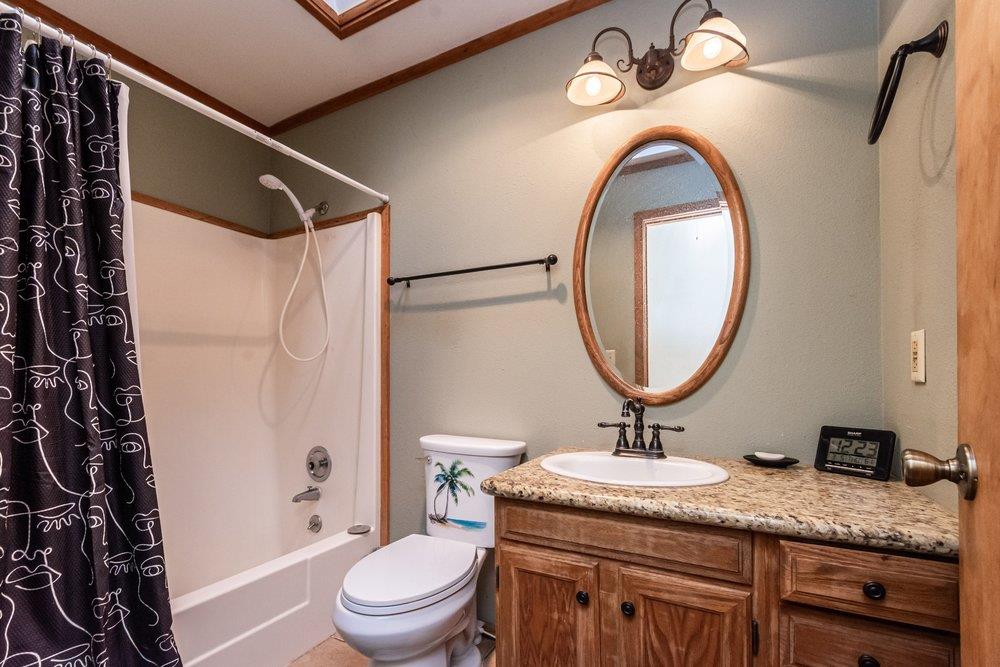 23870 Tokayana Way Colfax, CA 95713 - Photo 40 of 93 a bathroom with a granite countertop sink a mirror a toilet and a shower