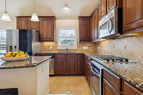 a kitchen with granite countertop a sink a stove and a refrigerator