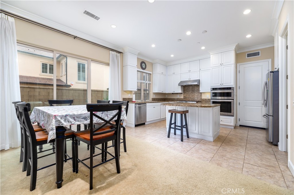 71 Thornapple Irvine, CA 92620 - Photo 30 of 33 a kitchen with stainless steel appliances kitchen island granite countertop a table and chairs in it