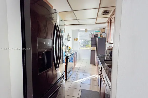 a kitchen with stainless steel appliances granite countertop a refrigerator a stove and a sink with wooden cabinets