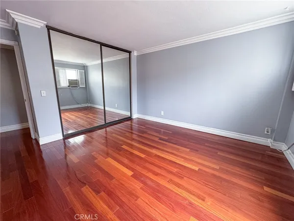 an empty room with wooden floor and mirror