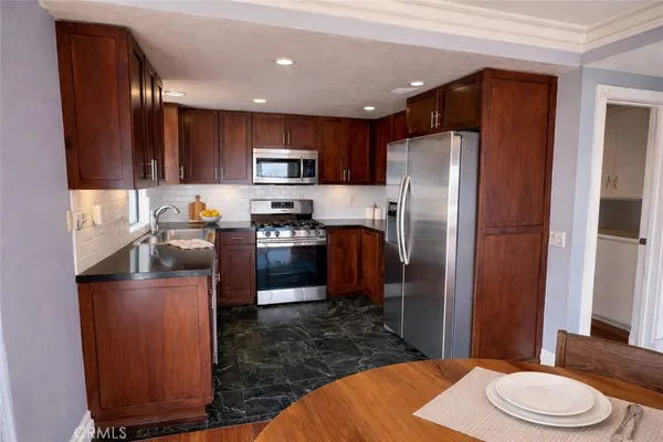 a kitchen with stainless steel appliances granite countertop a refrigerator a stove a sink a washer and dryer