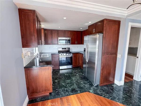 a kitchen with stainless steel appliances granite countertop a refrigerator a stove top oven a sink and dishwasher