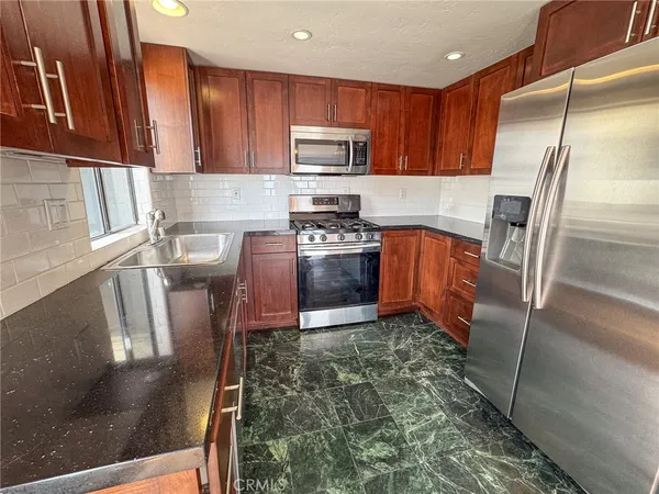 a kitchen with stainless steel appliances granite countertop a refrigerator a stove top oven a sink and dishwasher