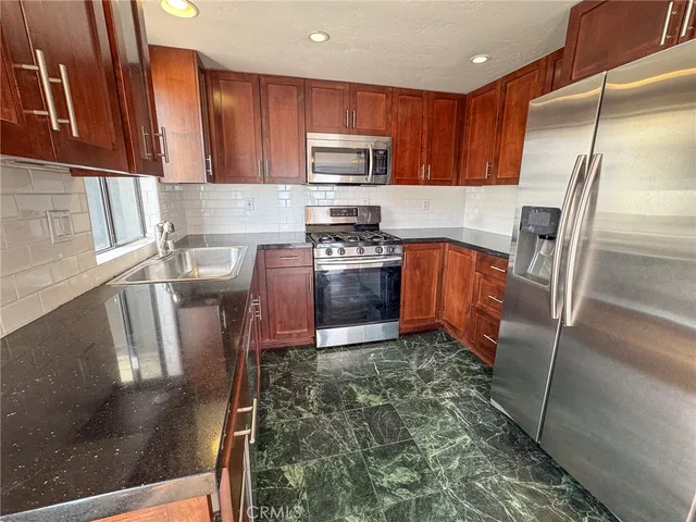 a kitchen with stainless steel appliances granite countertop a refrigerator a stove top oven a sink and dishwasher