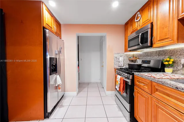 a kitchen with stainless steel appliances granite countertop a refrigerator and a stove top oven
