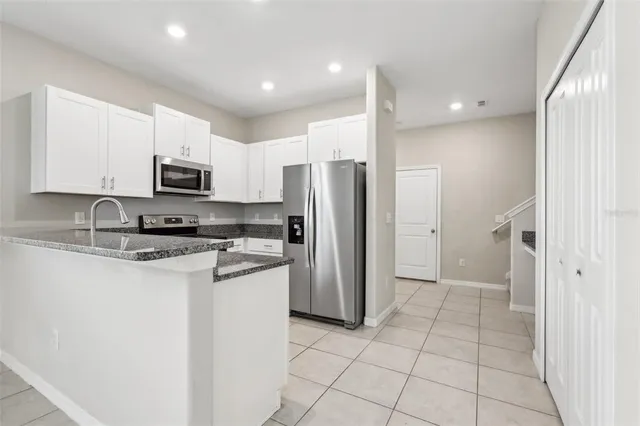 a kitchen with white cabinets and refrigerator
