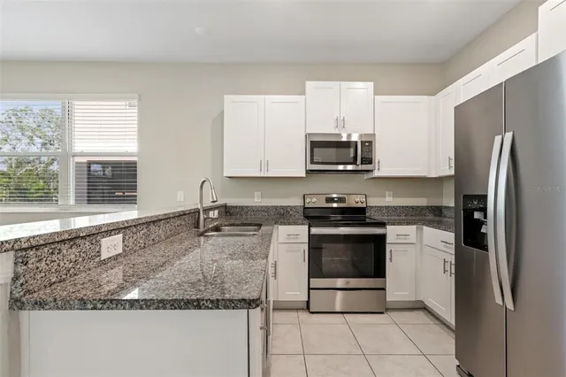 a kitchen with stainless steel appliances granite countertop a refrigerator and a stove top oven