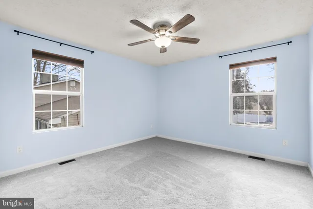an empty room with a window and a ceiling fan