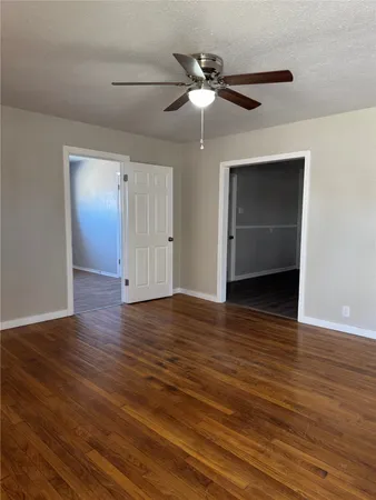 a view of empty room with wooden floor and ceiling fan