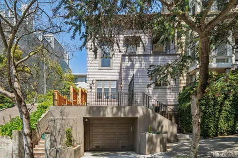 a front view of a house with a tree