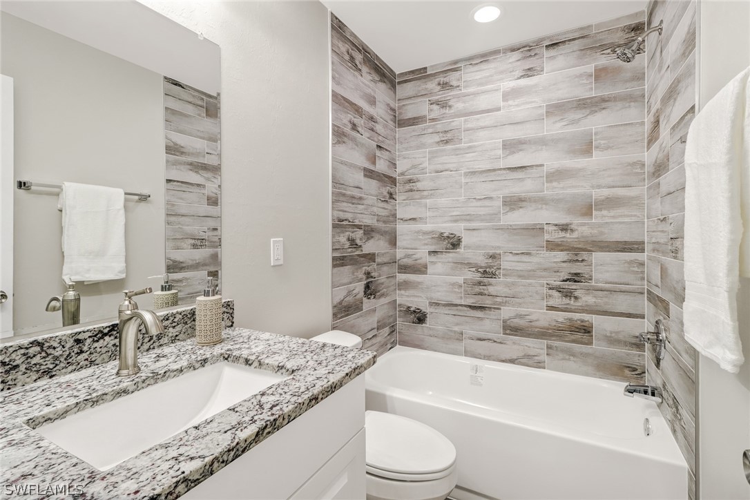 112 Rowland Road Lehigh Acres, FL 33936 - Photo 17 of 22 a bathroom with a granite countertop bathtub shower sink vanity and toilet