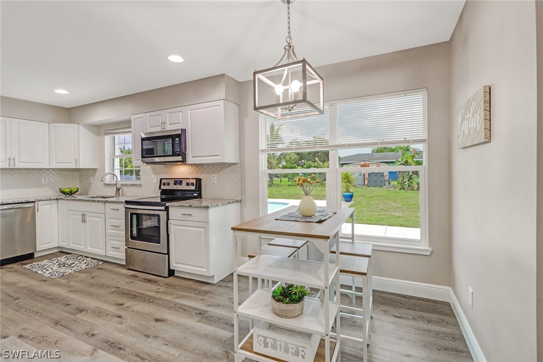 112 Rowland Road Lehigh Acres, FL 33936 - Photo 6 of 22 a kitchen with stainless steel appliances a stove a sink a microwave a refrigerator and cabinets