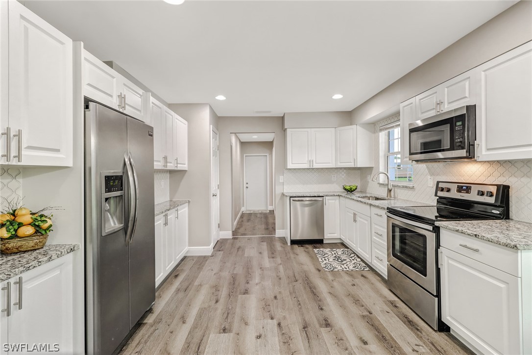 112 Rowland Road Lehigh Acres, FL 33936 - Photo 8 of 22 a kitchen with stainless steel appliances a refrigerator sink and microwave