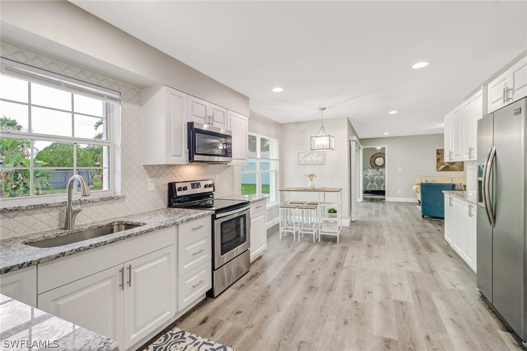112 Rowland Road Lehigh Acres, FL 33936 - Photo 9 of 22 a kitchen with white cabinets and stainless steel appliances