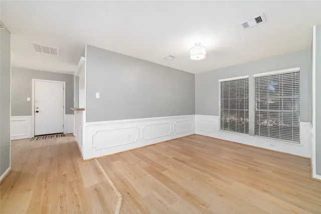 a view of an empty room with a window and wooden floor