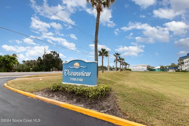 a view of a sign board with buildings in the background