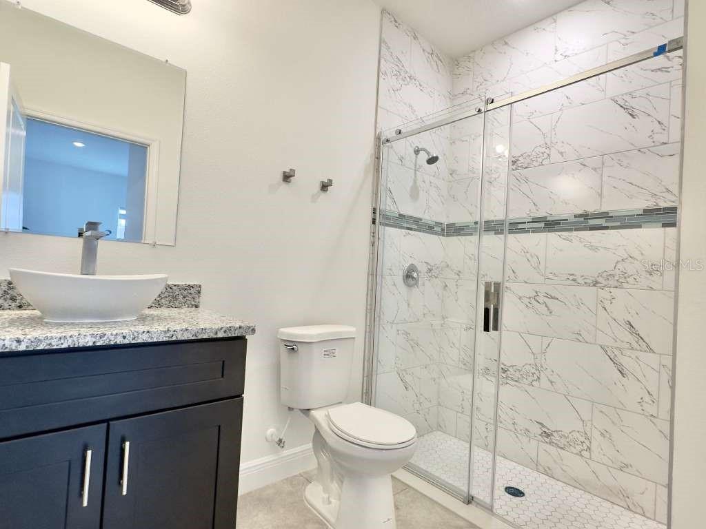 15885 Southwest 35th Court Road, Unit 1 Ocala, FL 34473 - Photo 9 of 27 a bathroom with a granite countertop sink toilet and shower