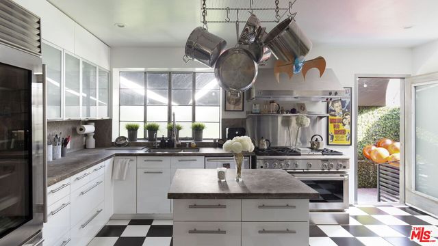 a kitchen with kitchen island granite countertop a sink a stove and cabinets