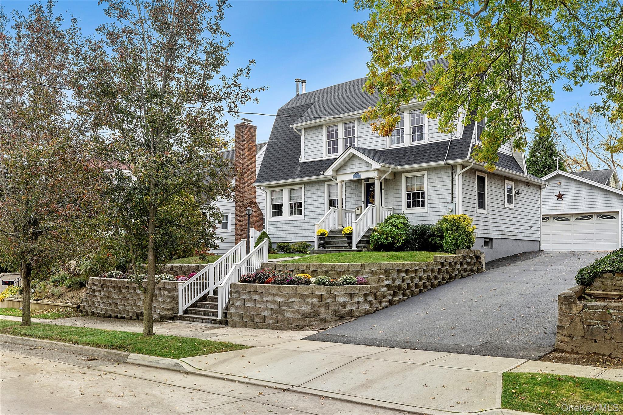 Colonial inspired home featuring roof with shingles, an outbuilding, a chimney, and a garage