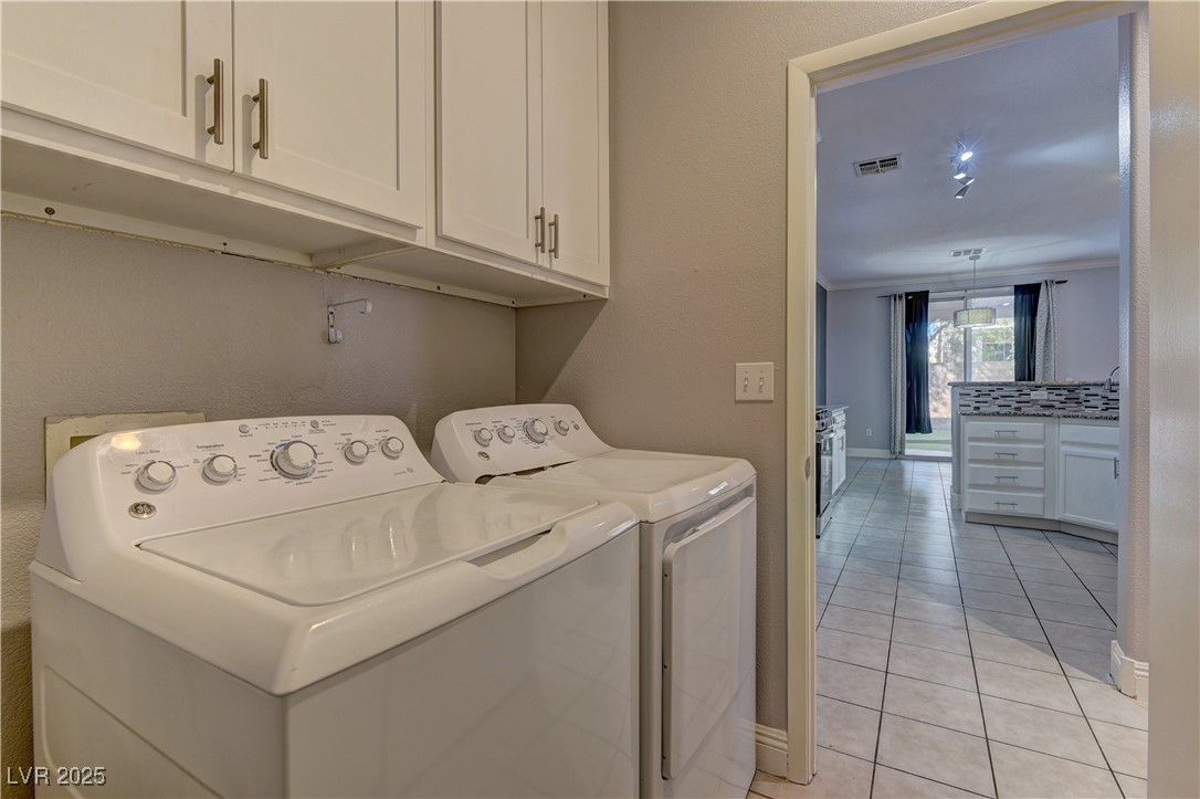 10654 Solar Hawk Avenue Las Vegas, NV 89129 - Photo 15 of 26 Washroom with cabinet space, light tile patterned flooring, washing machine and clothes dryer, and a textured wall