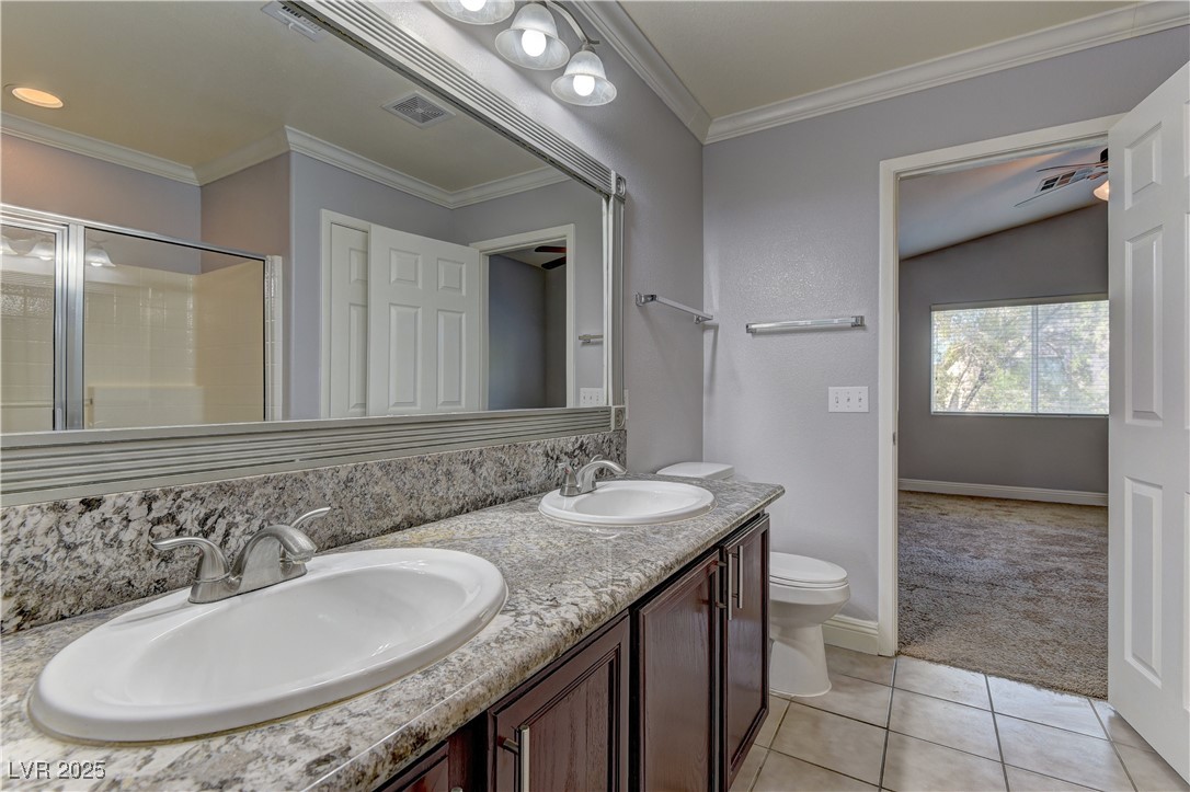 10654 Solar Hawk Avenue Las Vegas, NV 89129 - Photo 20 of 26 Full bath featuring light tile patterned floors, a stall shower, double vanity, ornamental molding, and light colored carpet
