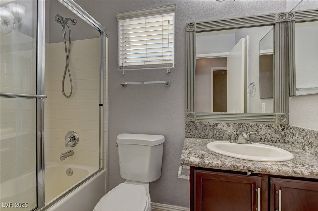 10654 Solar Hawk Avenue Las Vegas, NV 89129 - Photo 23 of 26 Bathroom featuring a textured wall, shower / bath combination with glass door, and vanity