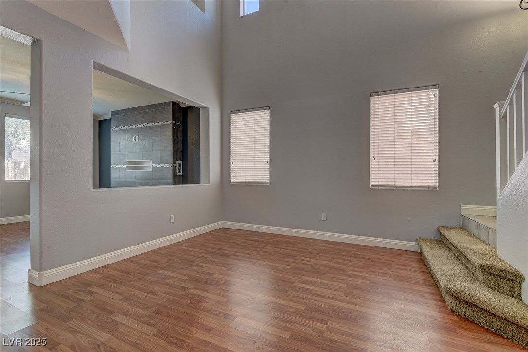 10654 Solar Hawk Avenue Las Vegas, NV 89129 - Photo 5 of 26 Unfurnished living room featuring stairs, wood finished floors, and a towering ceiling