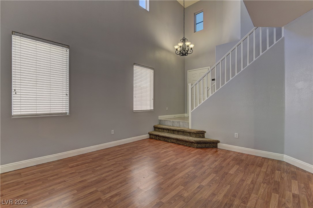 10654 Solar Hawk Avenue Las Vegas, NV 89129 - Photo 6 of 26 Unfurnished living room featuring wood finished floors, a chandelier, stairway, and a high ceiling