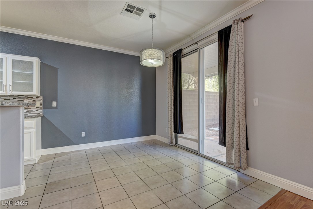 10654 Solar Hawk Avenue Las Vegas, NV 89129 - Photo 10 of 26 Unfurnished dining area featuring ornamental molding and light tile patterned flooring