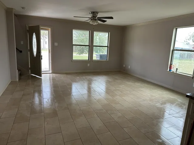 an empty room with chandelier fan and windows