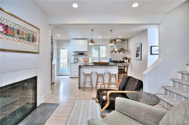 a living room with stainless steel appliances furniture a fireplace and a open kitchen view