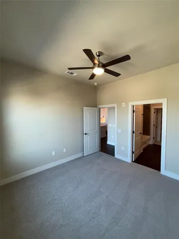 an empty room with ceiling fan and windows