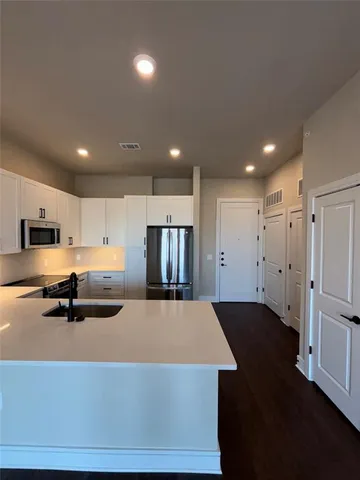 a kitchen with stainless steel appliances granite countertop a refrigerator a stove and a sink with wooden floor