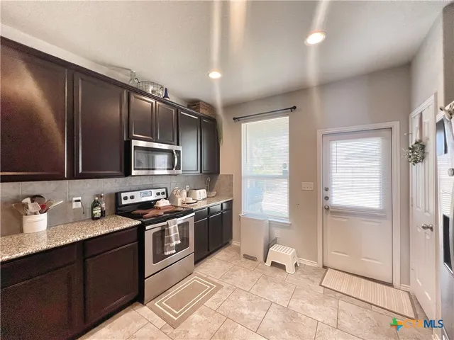 a kitchen with stainless steel appliances granite countertop a stove a sink and a refrigerator