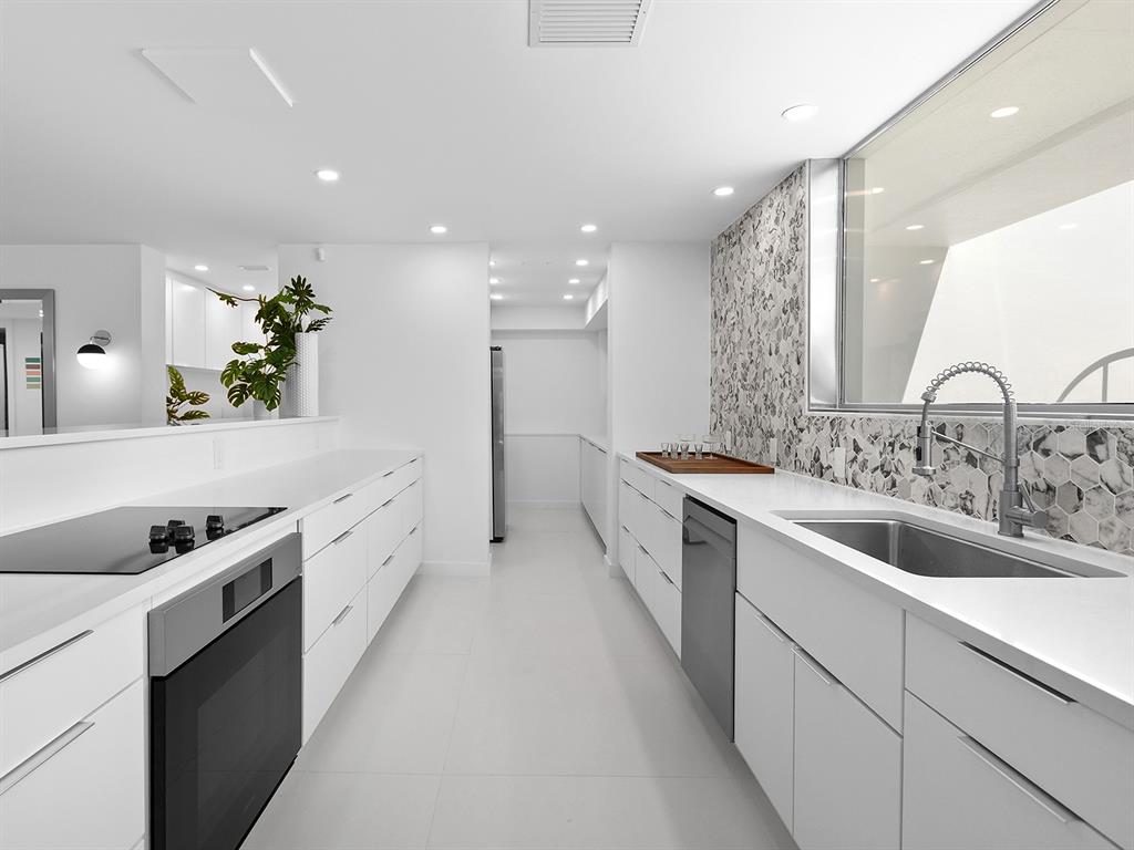 7647 Sanderling Road Sarasota, FL 34242 - Photo 24 of 75 a large white kitchen with a large counter top a sink a stove and a refrigerator