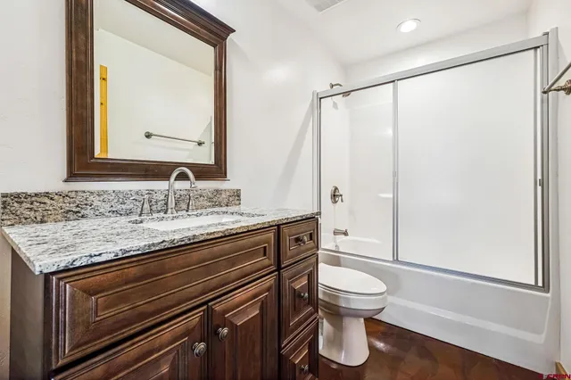 a bathroom with a granite countertop sink toilet and shower