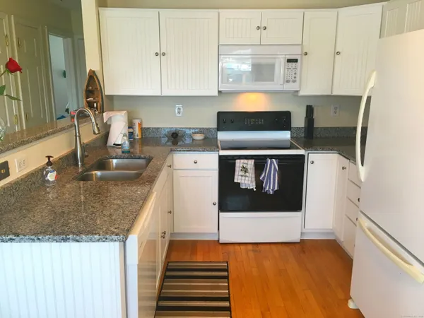 a kitchen with stainless steel appliances granite countertop a sink stove and white cabinets