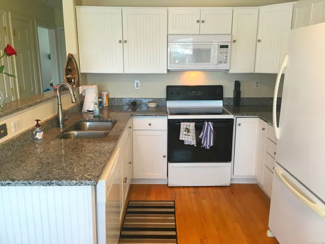 a kitchen with stainless steel appliances granite countertop a sink stove and white cabinets
