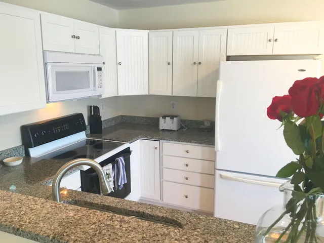 a kitchen with white cabinets and white appliances
