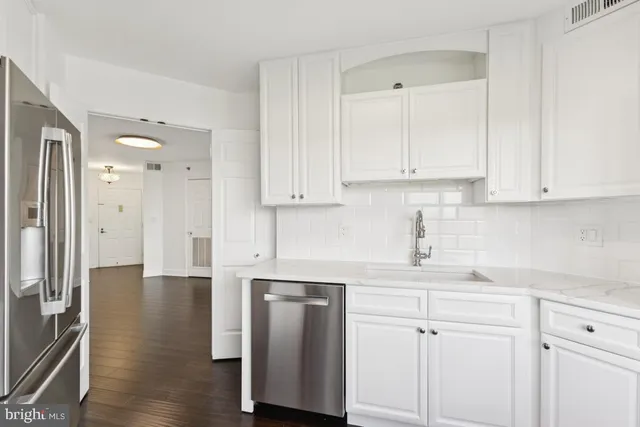 a kitchen with stainless steel appliances white cabinets and wooden floors