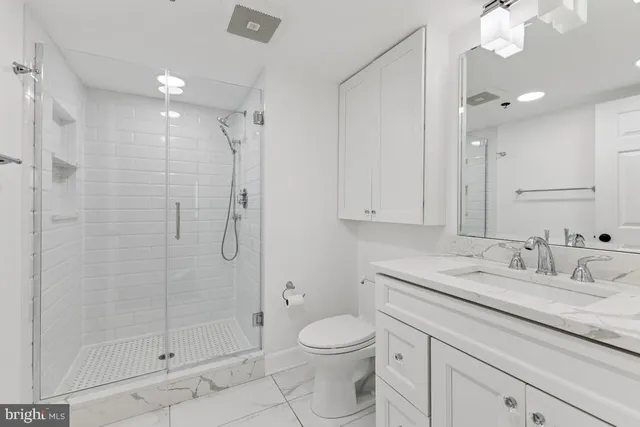 a bathroom with a granite countertop sink a toilet and shower
