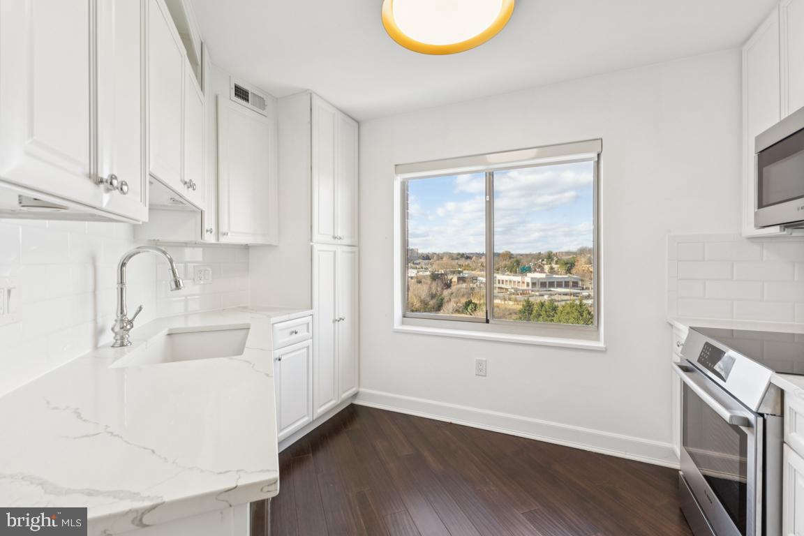 2151 Jamieson Avenue, Unit 1002 Alexandria, VA 22314 - Photo 9 of 25 a kitchen with stainless steel appliances a sink a stove a refrigerator and white cabinets with wooden floor