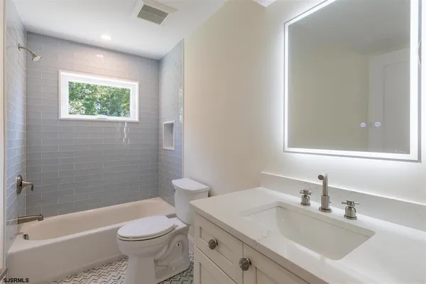 a bathroom with a sink a toilet a mirror a bathtub and shower