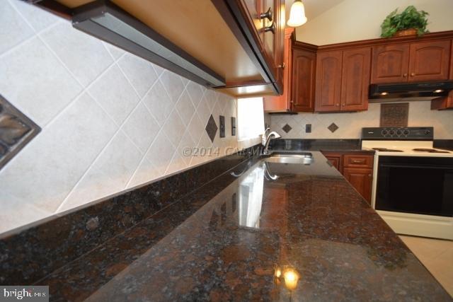 12 Mist Flower Road Ocean Pines, MD 21811 - Photo 18 of 42 a kitchen with granite countertop a sink a stove and wooden cabinets