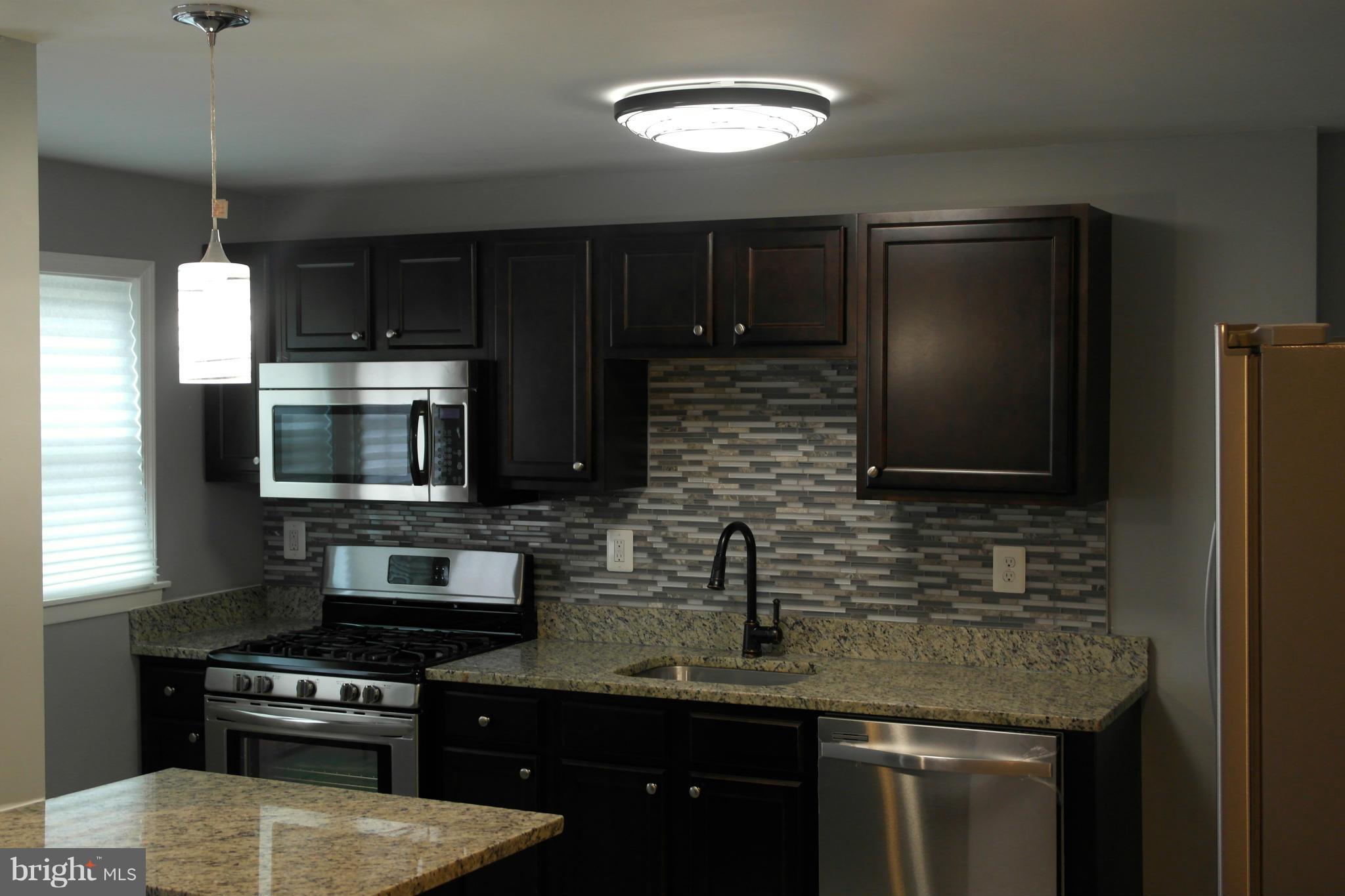 1225 Wicklow Road Baltimore, MD 21229 - Photo 2 of 17 a kitchen with stainless steel appliances granite countertop a sink stove and microwave